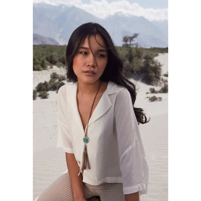 Woman in a white blouse with a necklace in a desert setting
