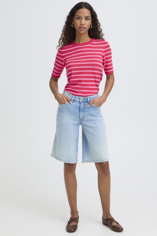 Woman wearing a pink striped shirt and light blue denim shorts on a white background
