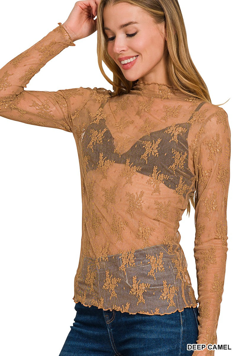 Woman wearing a sheer brown lace top with a bra visible underneath on a white background.