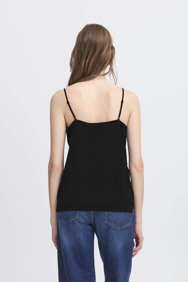 Woman wearing a black spaghetti strap top and blue jeans on a white background