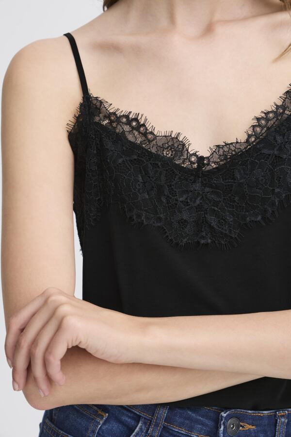 Black lace-trimmed top worn by a person on a plain background