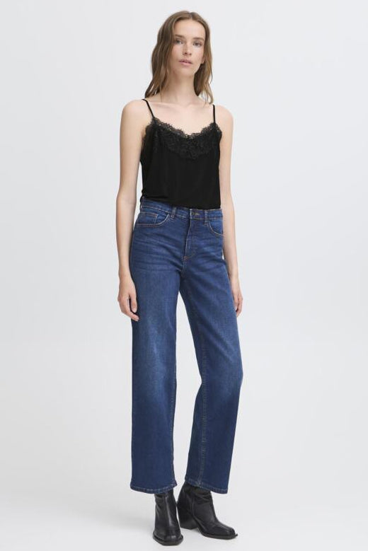 Woman wearing a black lace top and blue jeans on a white background