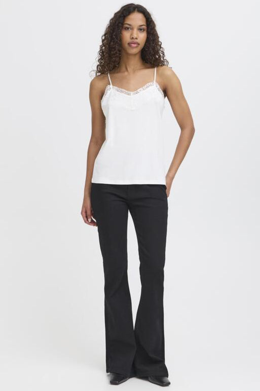 Woman wearing a white lace top and black pants on a white background