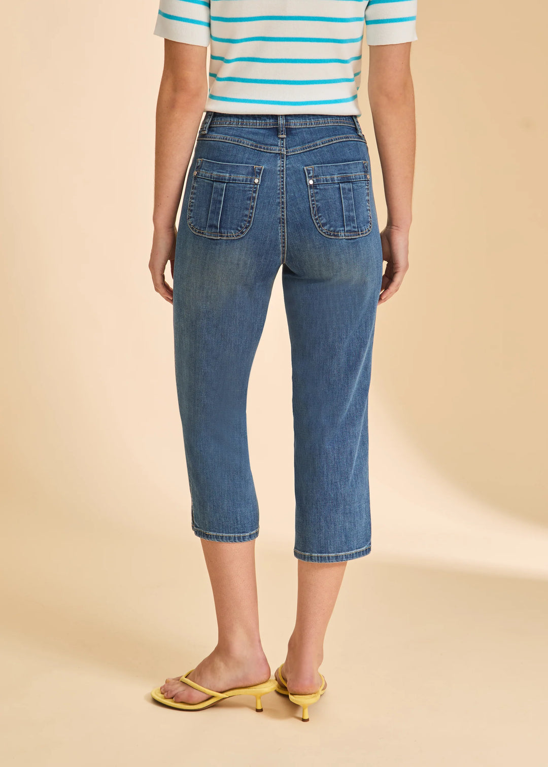 Person wearing blue jeans and a striped shirt on a beige background