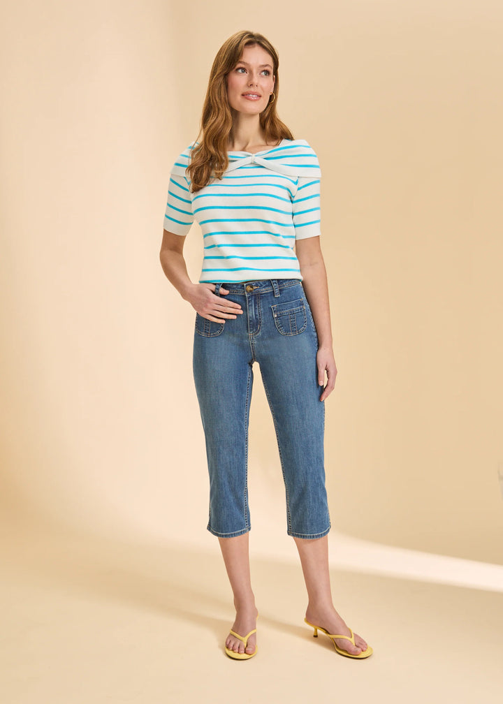 Woman wearing a striped shirt and blue jeans against a beige background