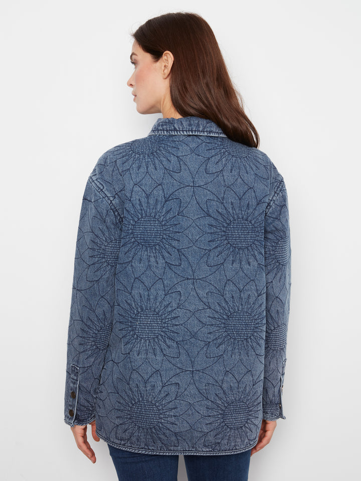 A woman shown from the back wearing a blue denim jacket with a large sunflower embroidery pattern, set against a plain white background.