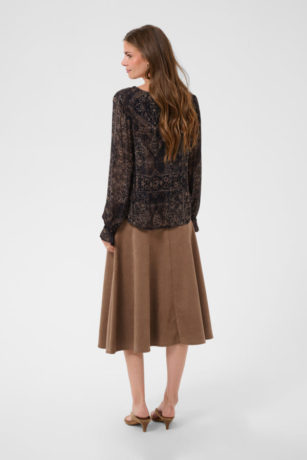 A woman is shown from the back wearing a black lace long-sleeve blouse and a brown A-line midi skirt, paired with brown heels, against a light gray studio background.