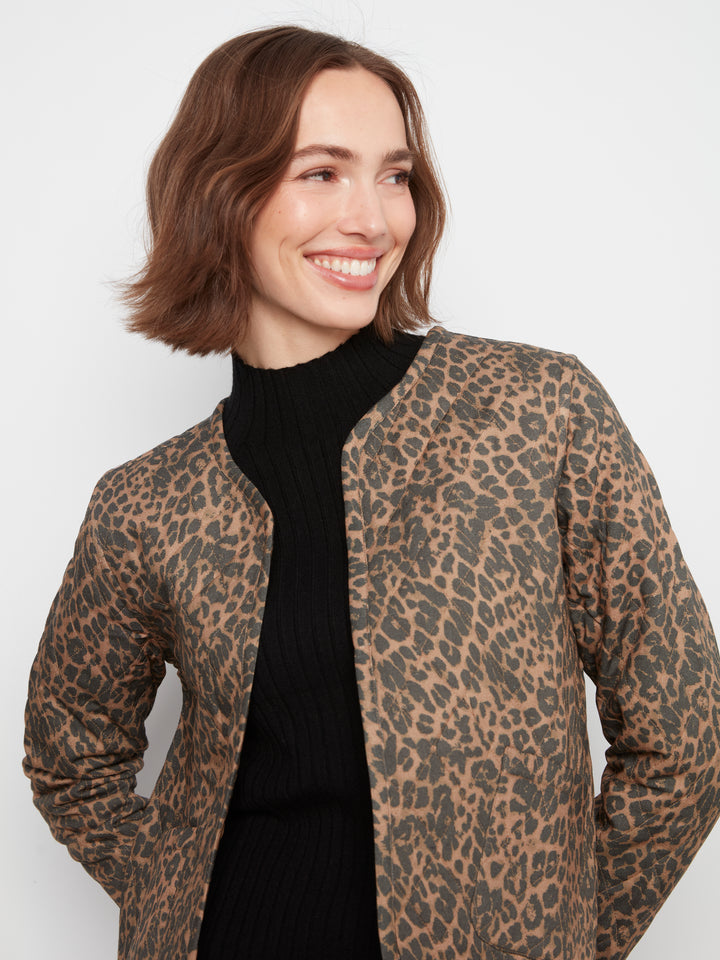 A woman wearing a brown and black leopard print jacket over a black ribbed turtleneck sweater, photographed against a plain light gray studio background.