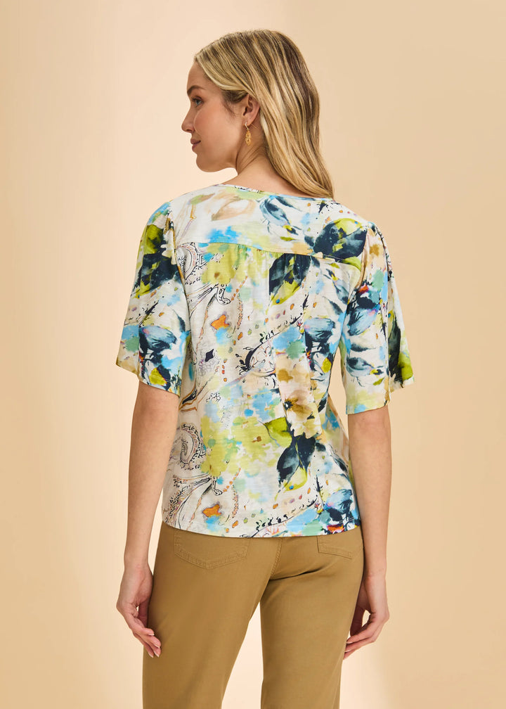 Woman wearing a colorful floral blouse against a beige background