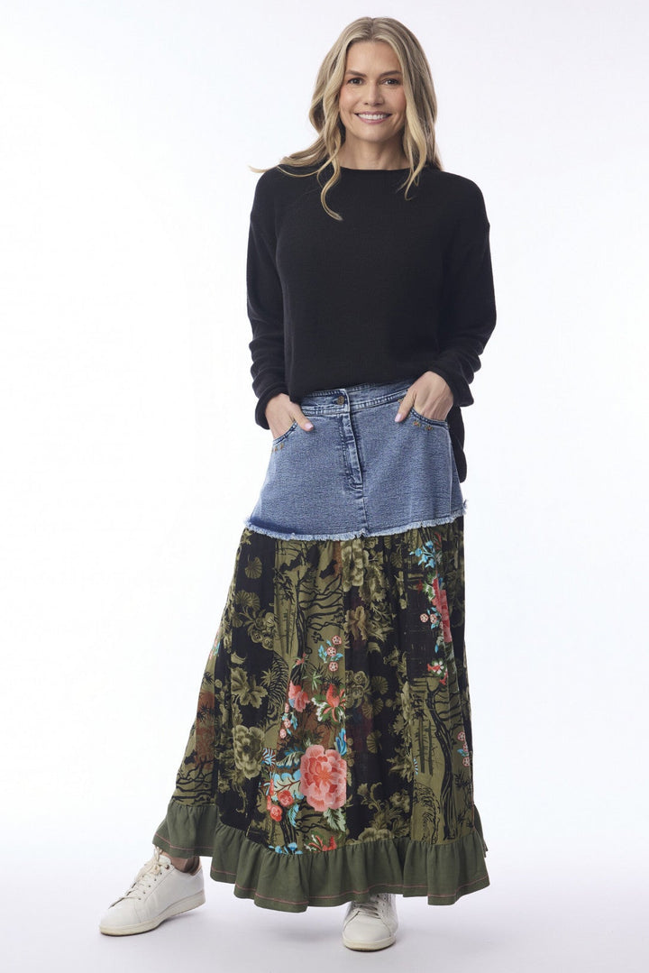 Woman wearing a black top, denim jacket, and floral skirt on a white background