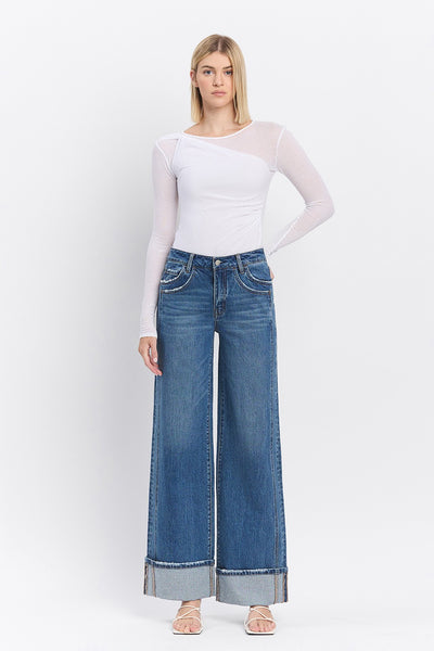 Woman wearing a white long-sleeve top and blue jeans on a white background