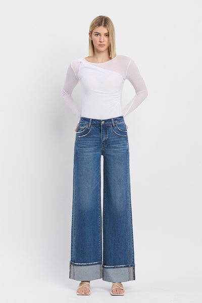 Woman wearing a white long-sleeve top and blue jeans on a white background