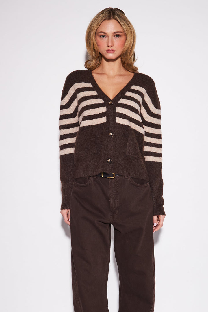Woman wearing a striped cardigan and brown pants on a white background