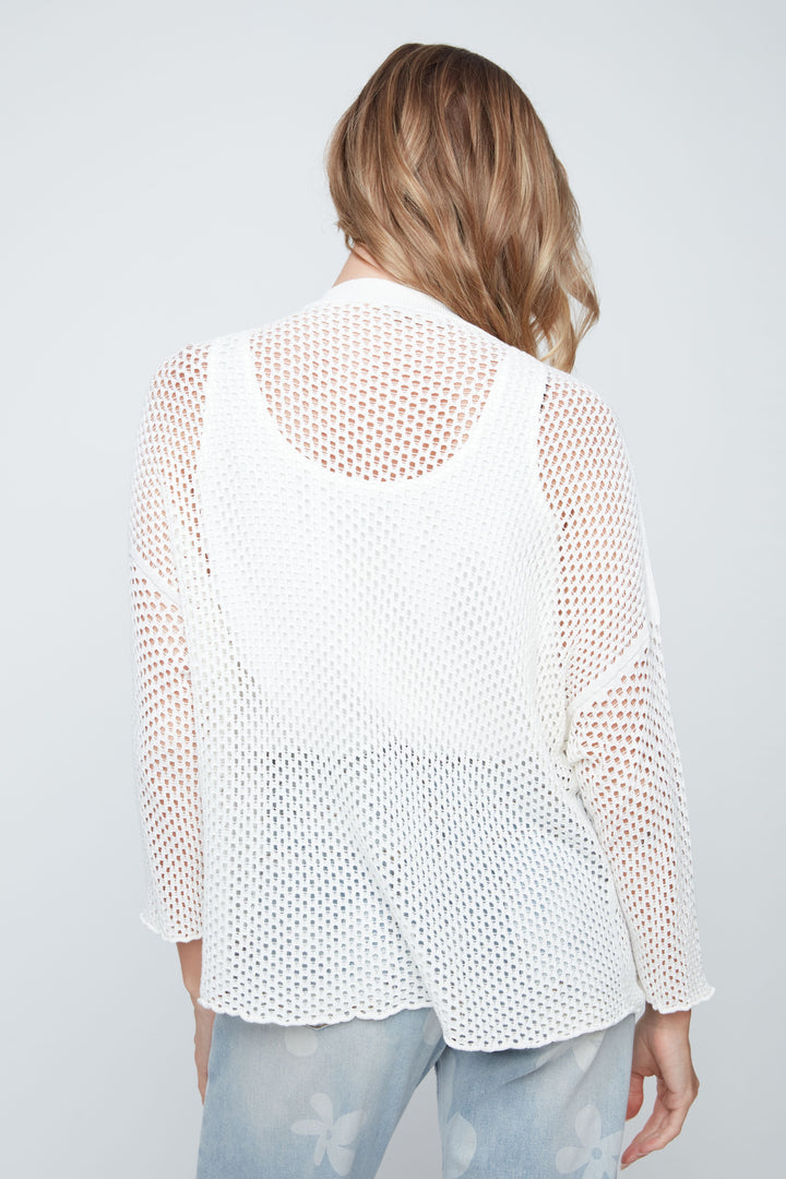 Woman wearing a white mesh top with a plain background