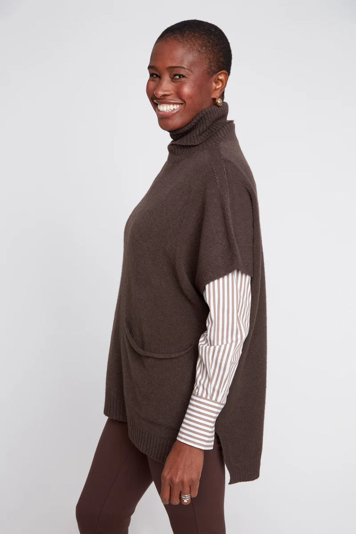 Woman wearing a brown poncho over a striped shirt on a white background