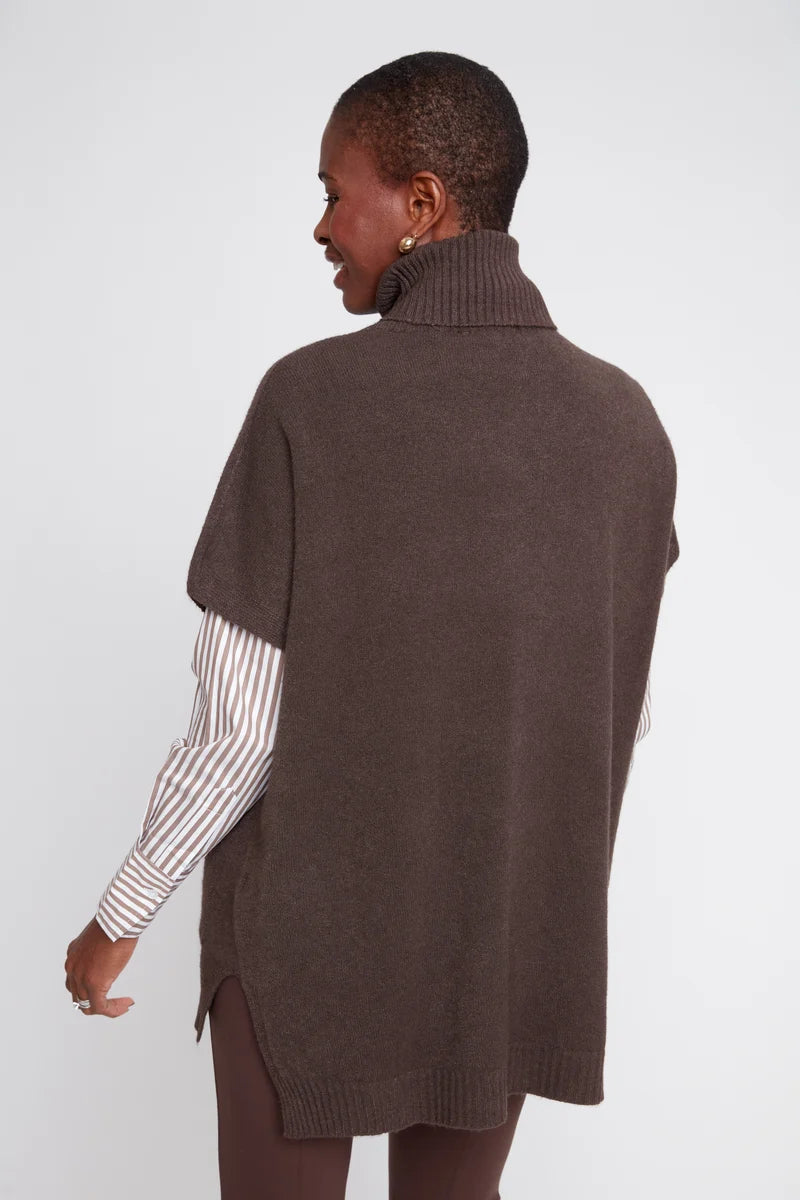 Person wearing a brown knitted vest over a striped shirt on a white background
