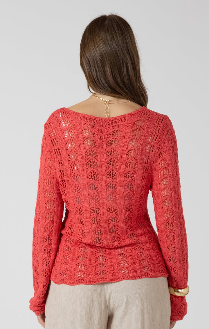 Woman wearing a red lace top and beige pants on a white background
