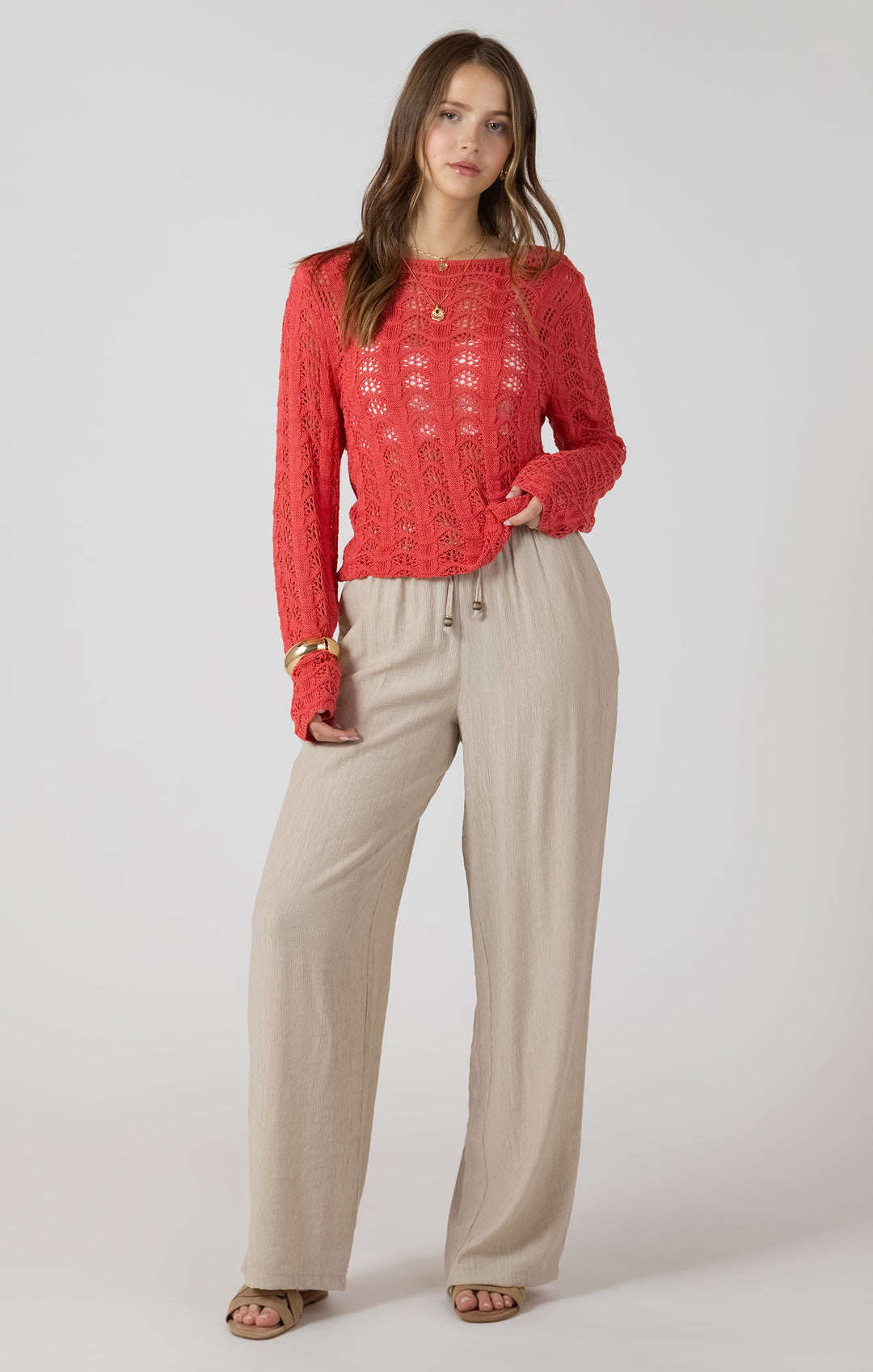 Woman wearing a red top and beige pants on a white background