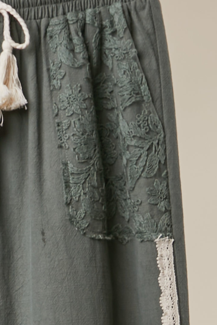 Dark green lace-trimmed pants with a beige background