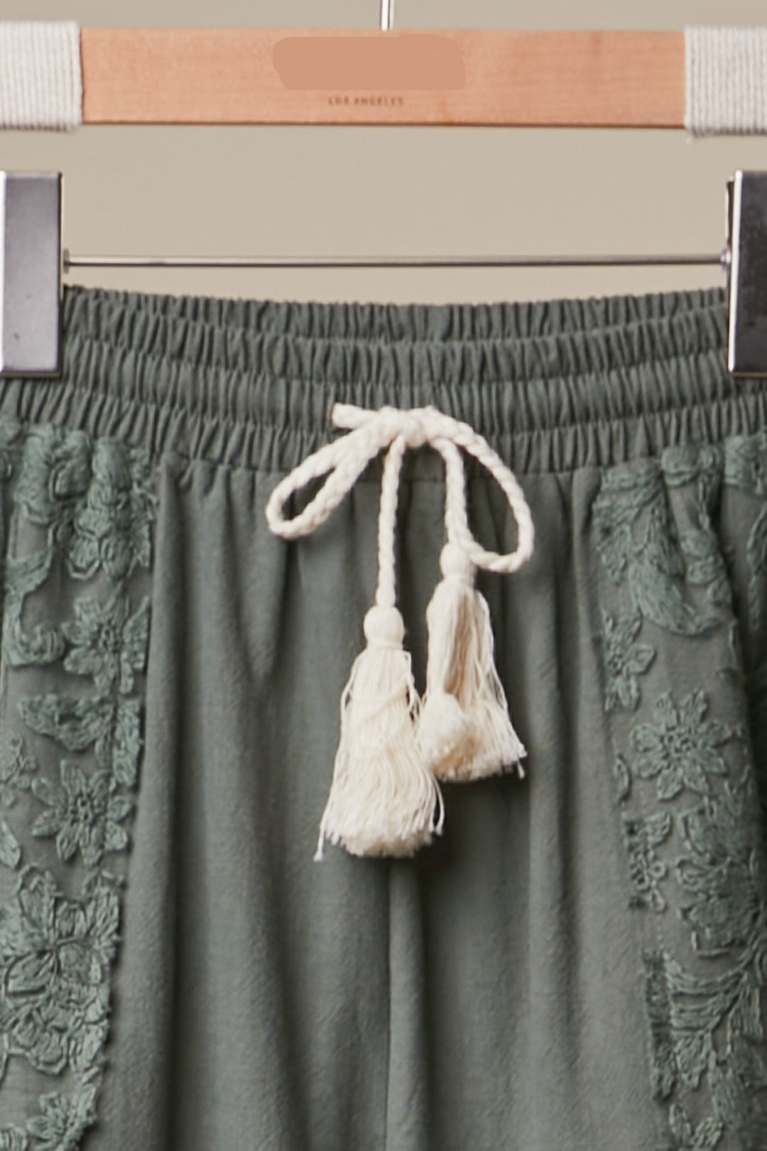 Green skirt with tassel details on a hanger with &