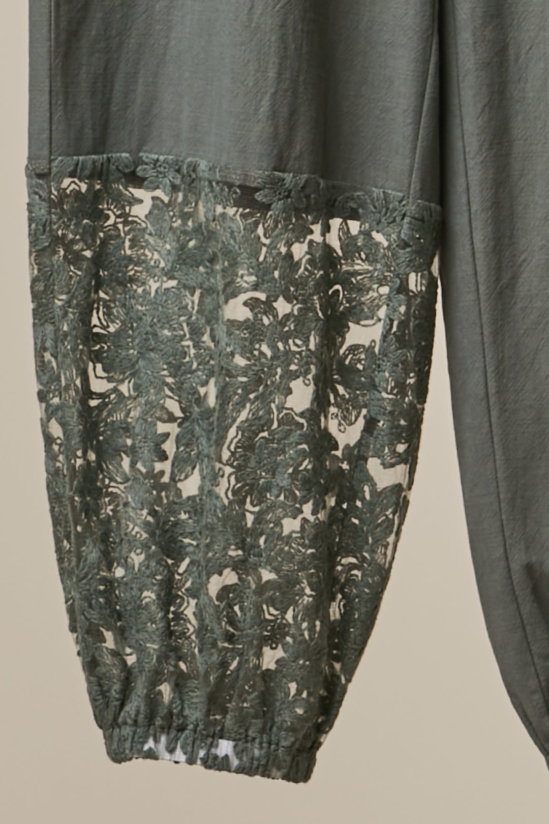 Dark gray pants with a camouflage pattern on the pocket against a neutral background