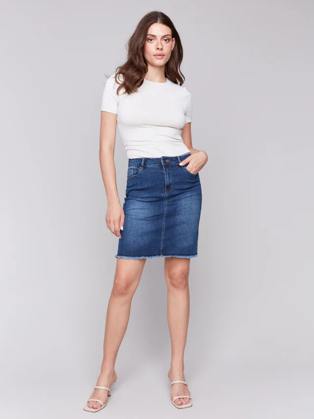 Woman wearing a white t-shirt and blue denim skirt on a gray background