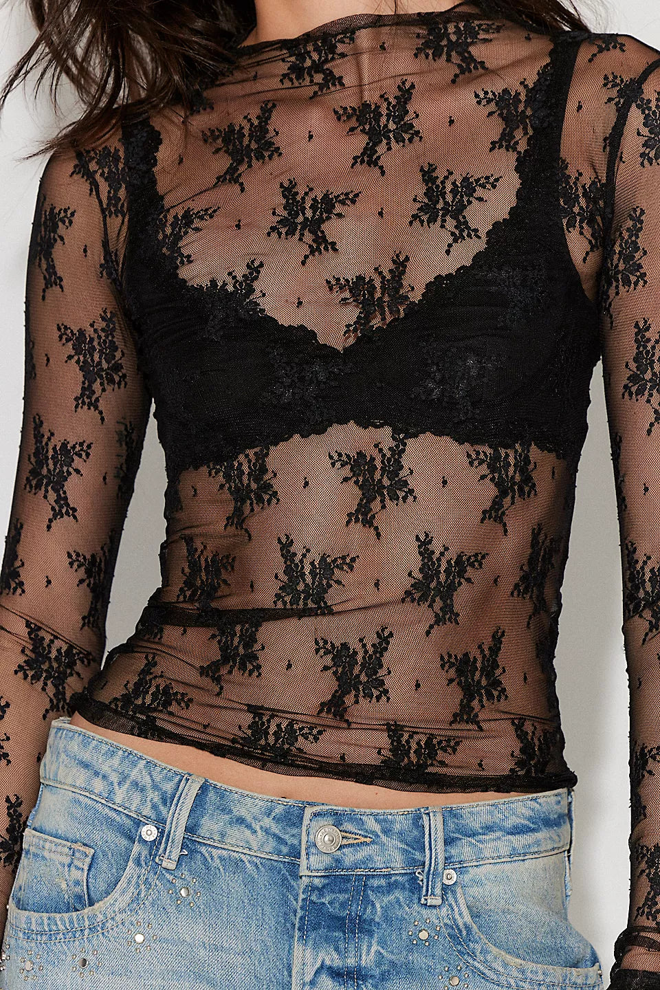 Black lace long-sleeve top with sheer design, worn over blue jeans.