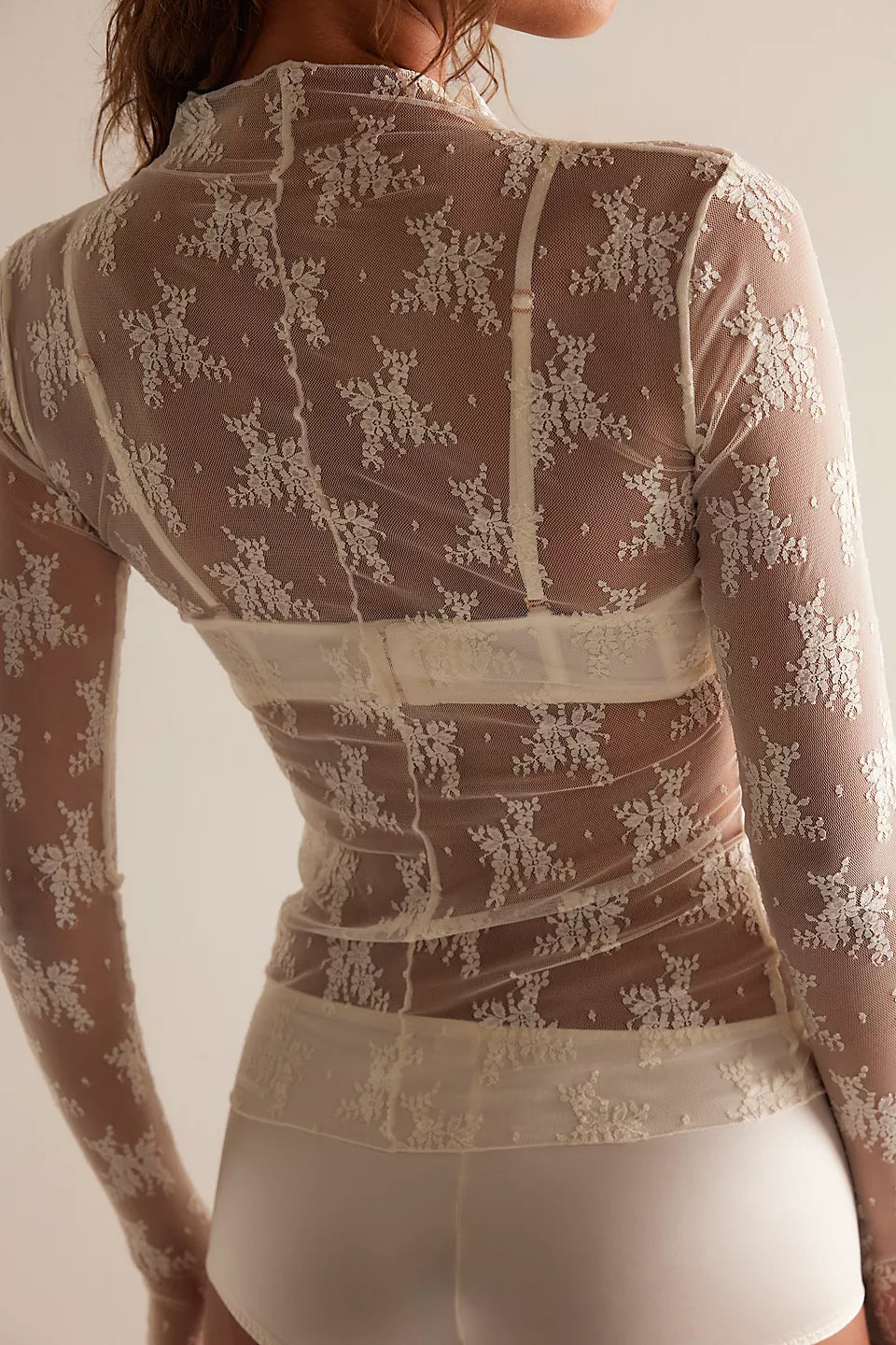 Sheer lace top with long sleeves on a plain background