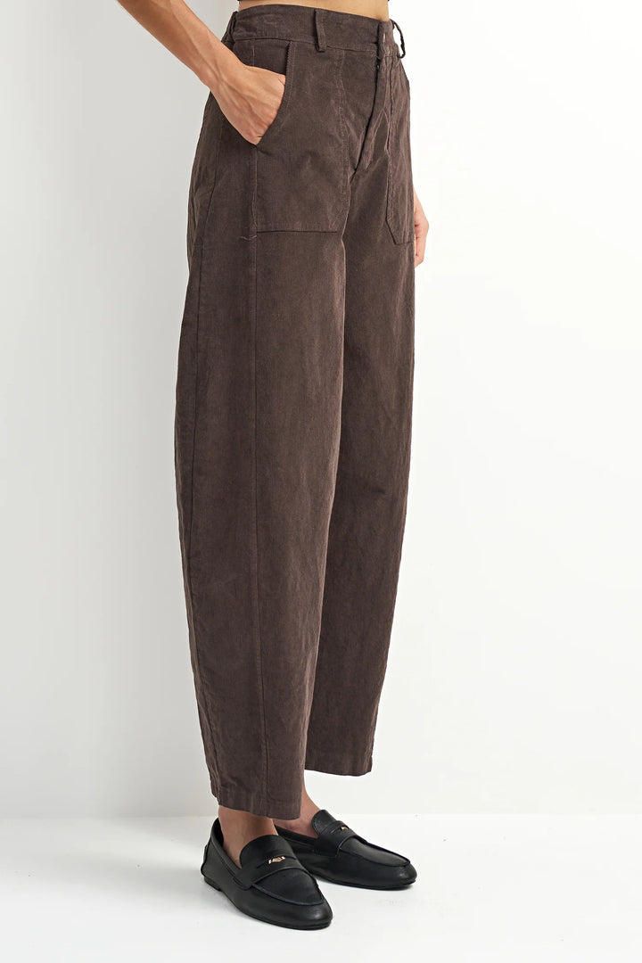 Brown corduroy pants worn by a person on a white background