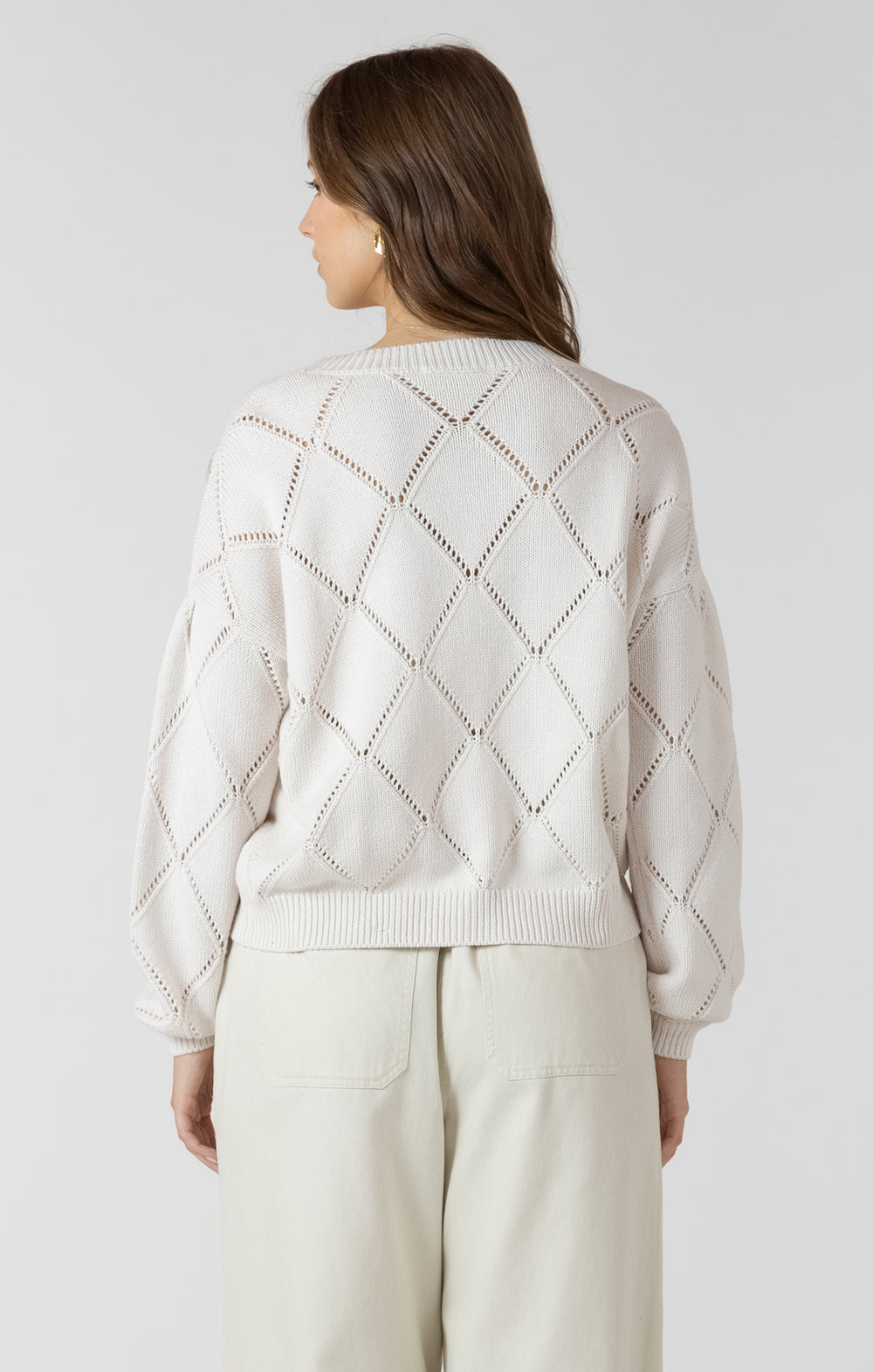 Woman wearing a light gray sweater with a diamond pattern on a white background