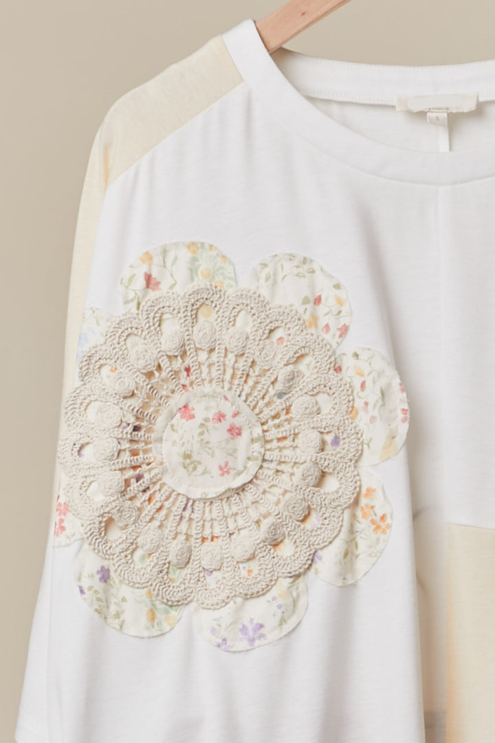 White shirt with a floral doily appliqué on a beige background