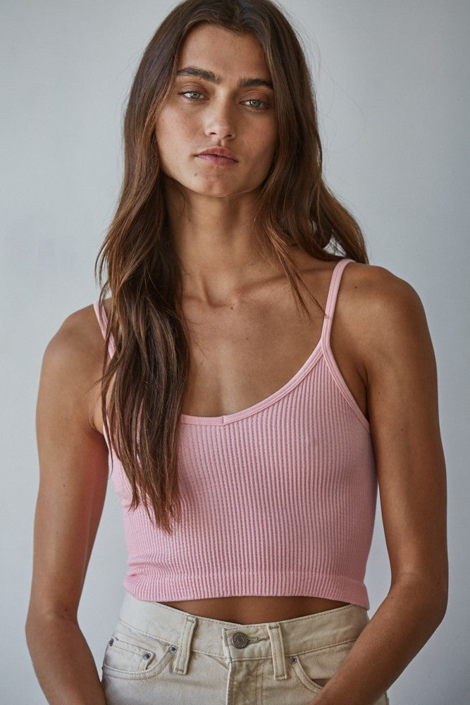 Woman wearing a pink ribbed tank top against a plain background