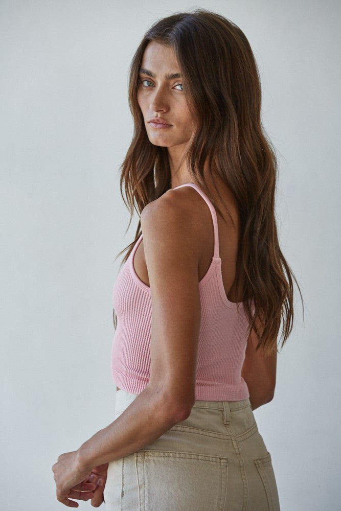 Woman wearing a pink ribbed tank top against a plain background