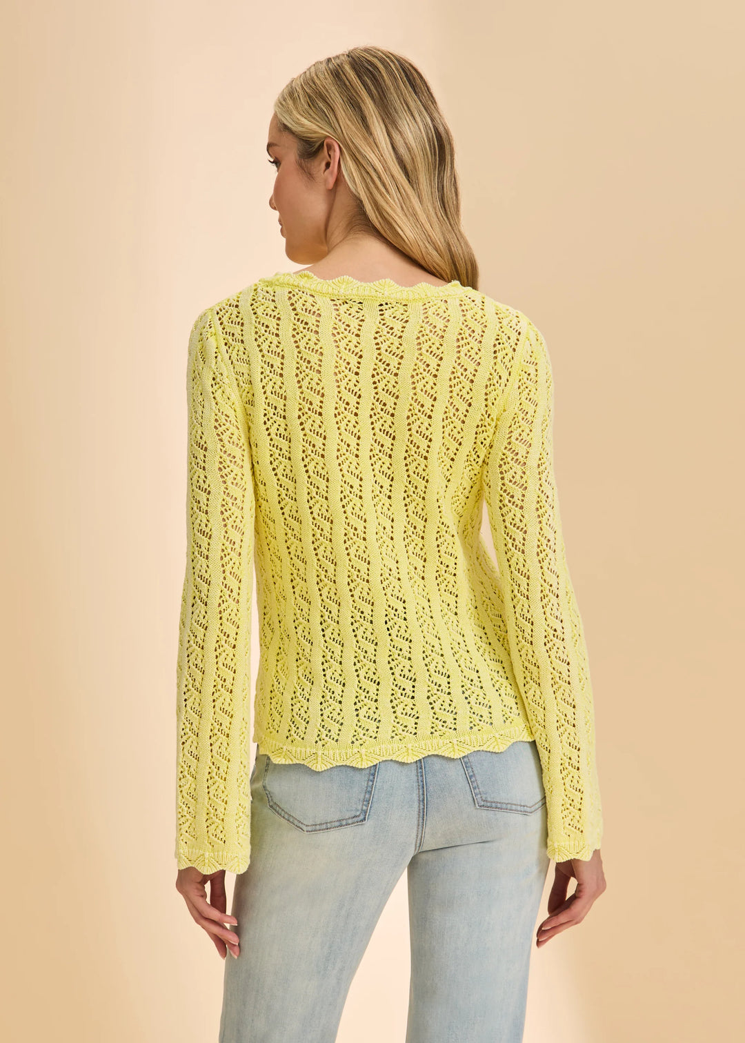 Woman wearing a yellow knitted sweater against a beige background