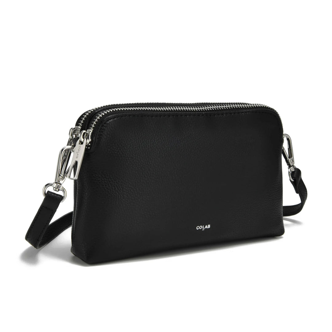 Black crossbody bag with silver zippers on a white background