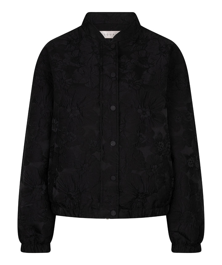 A black cropped jacket with a subtle tonal floral jacquard pattern, featuring a stand collar, button-front closure, and elasticized cuffs and hem, shown against a plain white background.