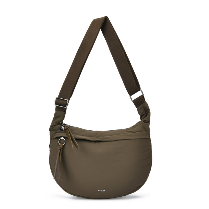 An olive green nylon shoulder bag with a wide adjustable strap, featuring a front zippered pocket with a tassel zipper pull and a small white &