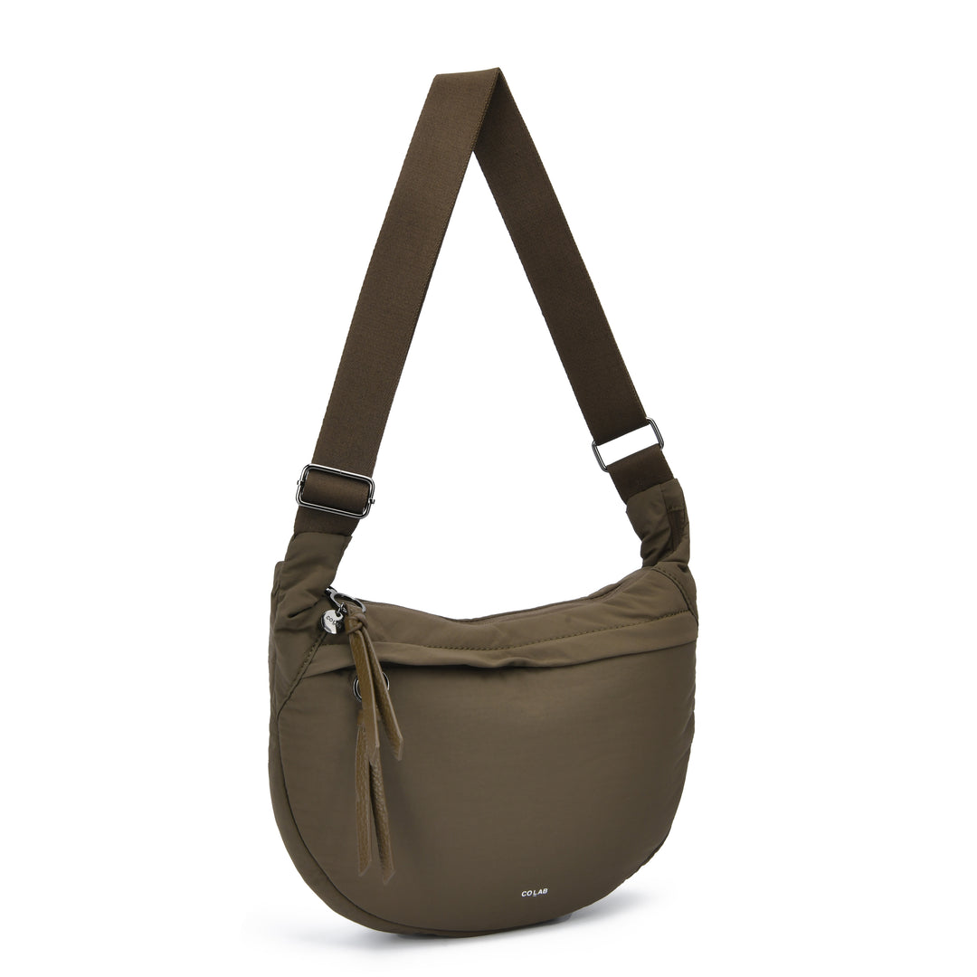 An olive green semi-circular crossbody bag with a matching adjustable shoulder strap, shown on a clean white background. The brand name &