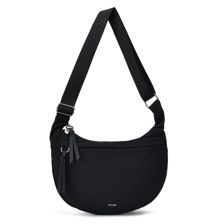 A black crescent-shaped shoulder bag with an adjustable shoulder strap, a front zippered pocket with a tassel, and a small white &