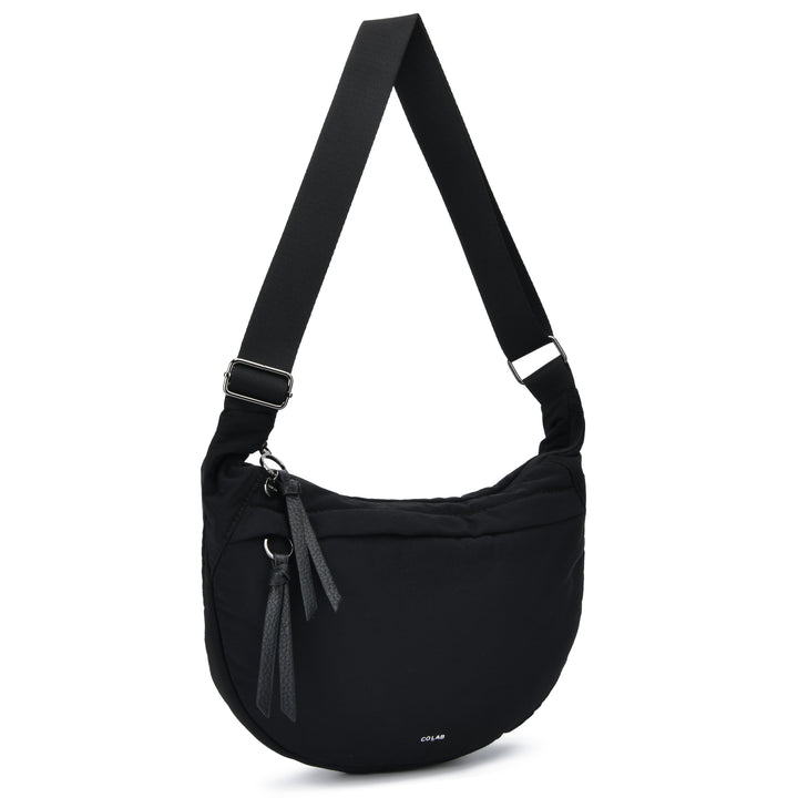 A black nylon shoulder bag with an adjustable webbing strap, a front zippered pocket with leather tassel pulls, and a small white &