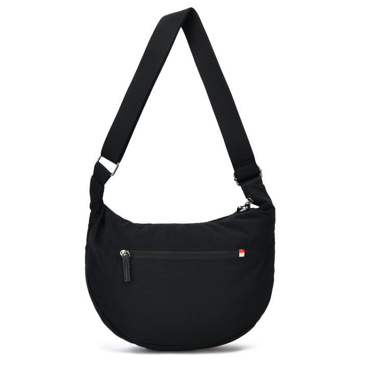 A black crescent-shaped shoulder bag with an adjustable shoulder strap, a front zippered pocket, and a small red and white logo tab on the right side, shown against a plain white background.