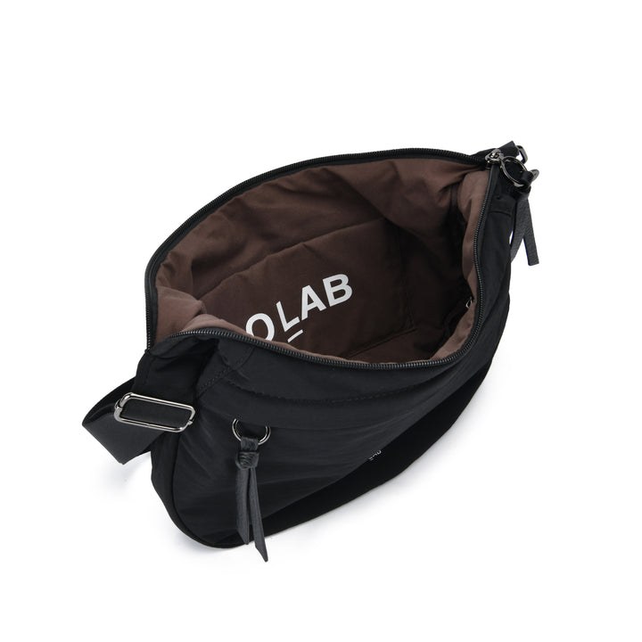 A black nylon crossbody bag shown open from an overhead angle, revealing a brown interior lining with the brand name &