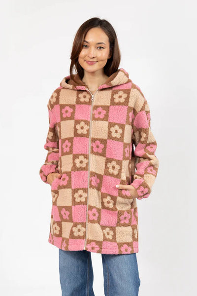 Woman wearing a checkered coat with pink and beige squares on a white background