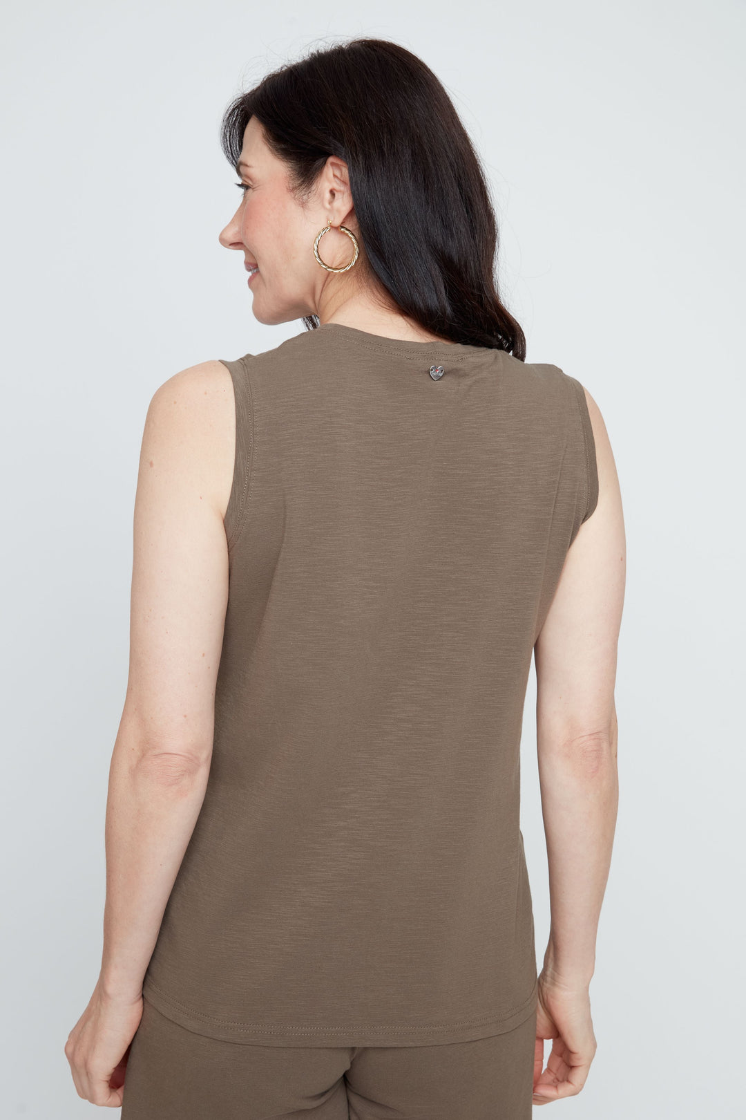 Woman wearing a brown sleeveless top and shorts on a white background