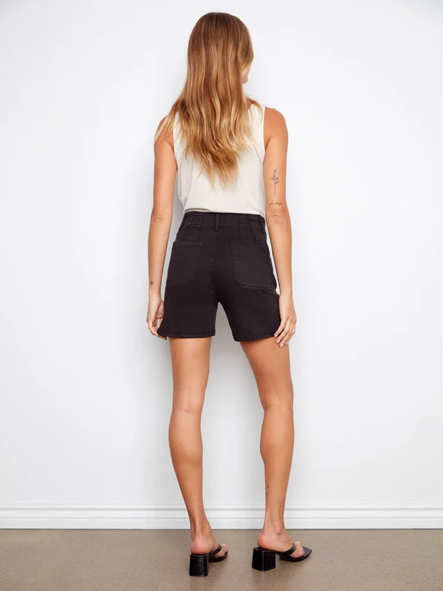 Person wearing black shorts and a white top against a plain background