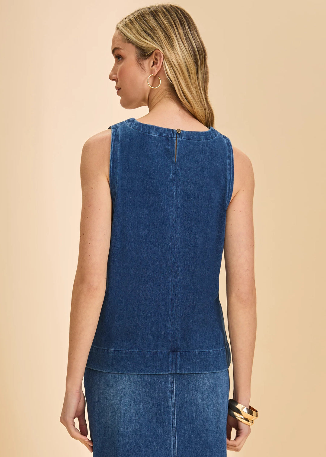 Woman wearing a blue denim dress against a beige background