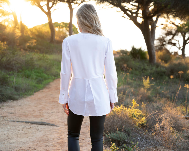 Person wearing a white shirt and black pants walking on a dirt path in a natural setting.