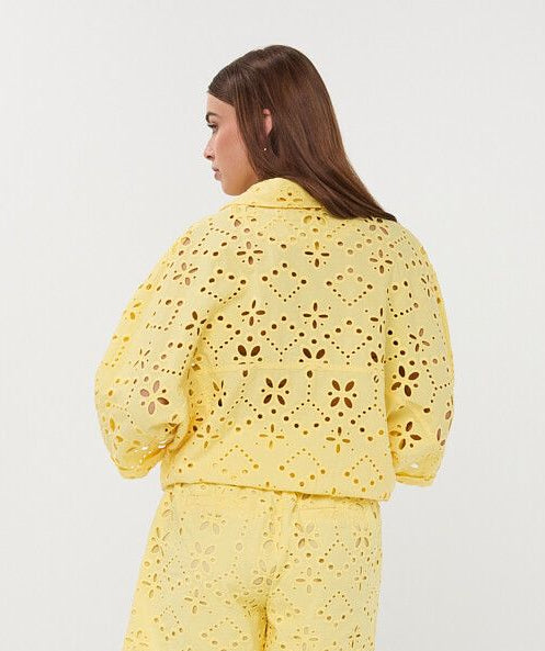Woman wearing a yellow crochet outfit on a white background