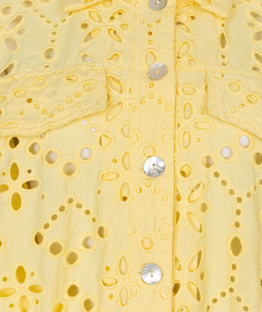Close-up of a yellow lace garment with floral patterns and button details.