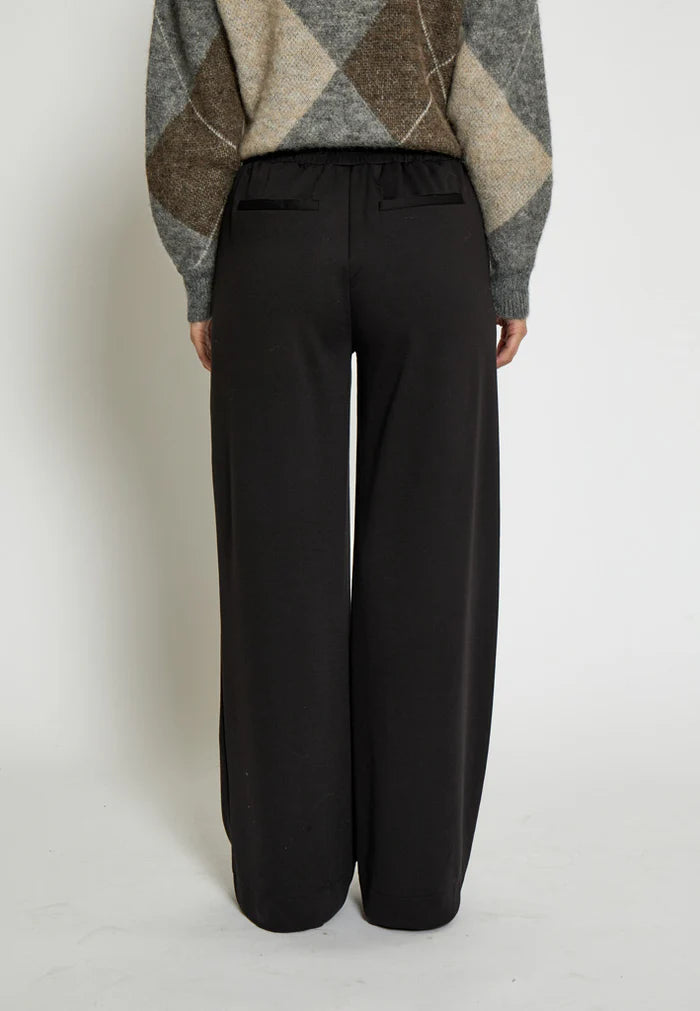 Person wearing black wide-leg pants and a patterned sweater on a white background